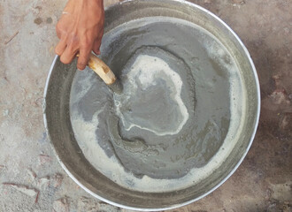 Hand of a person mixing cement in a bowl