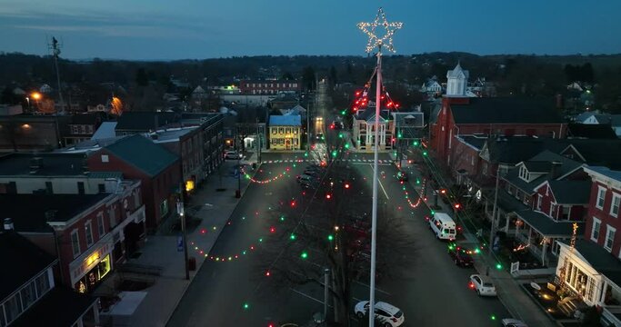 Cars drive through town decorated with lights and star at night. Christmas theme. Aerial establishing shot.