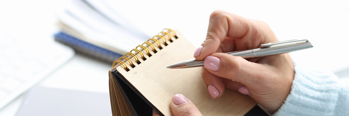 Blank notepad for writing planning of day in female hand with pen