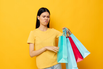 woman in a yellow T-shirt with multicolored shopping bags isolated background unaltered