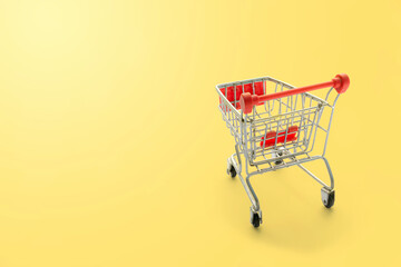 shopping trolley on yellow background with some copy space.