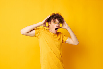 Fototapeta na wymiar portrait of a young curly man wearing stylish glasses yellow t-shirt posing Lifestyle unaltered