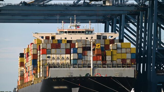 Container ship loading and unloading in deep sea port, telephoto view of business logistic import and export freight transportation. Time-lapse