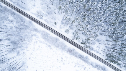 Aerial top down drone shot of Snowy forest road and two white cars. Forest road from above. White...