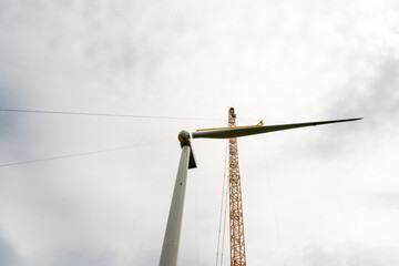 Obraz premium Construction of a wind power generator for renewable energy, Turbine hangs on crane hook at wind turbine construction site. Timelapse. 풍력발전기, 풍력터빈 설치, 신재생에너지.