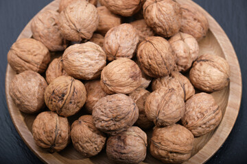 Walnut on black top view. Group of walnuts on a black background. Nuts on a wooden plate.