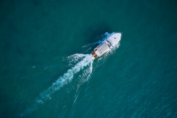 Obraz premium White yacht on the water top view. White boat on blue water aerial view. Boat in motion top view.