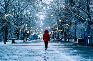 person in red jacket walking in snowy park in a winter morning