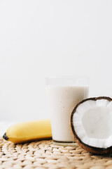 white healthy smoothie made of banana and fresh coconut, in a glass glass. healthy breakfast, healthy lifestyle