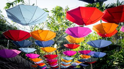 Fototapeta na wymiar Many umbrellas of different colors hang in the garden, giving people a relaxed feeling.