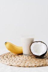 white healthy smoothie made of banana and fresh coconut, in a glass glass. healthy breakfast, healthy lifestyle