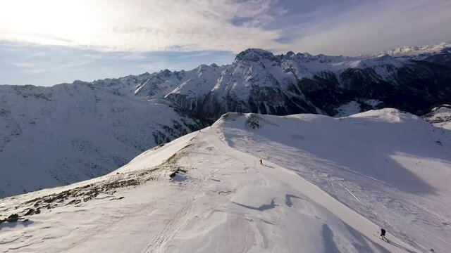 Dive down snowy mountain and ski piste in swiss alps, aerial fpv drone footage