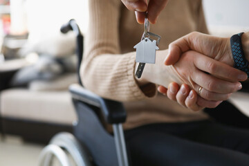 Realtor give keys from new accommodation to woman in wheelchair - obrazy, fototapety, plakaty