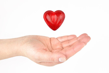 Glass heart over a woman's hand on a light background.