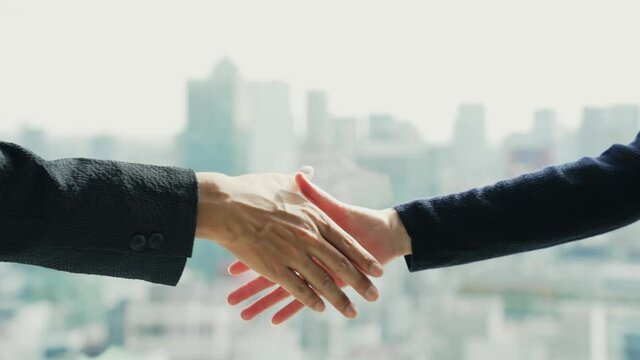 Couple of people shaking hands in front of the city.
