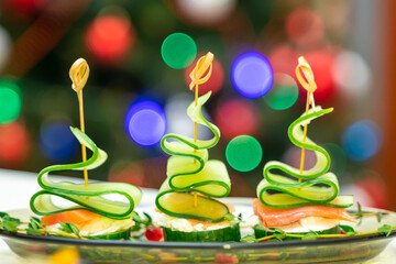 Festive canapes with salmon and cucumber in the form of a Christmas tree on a family holiday table. Banquet, buffet