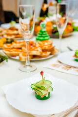 Festive canapes with salmon and cucumber in the form of a Christmas tree on a family holiday table. Banquet, buffet