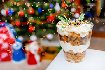 Christmas trifles cakes in a glass on the background of a Christmas tree with a garland