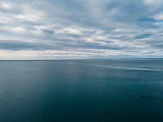 Aerial view over the sea with beautiful gray clouds illuminated by the sun