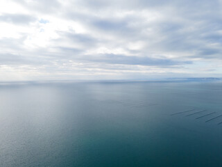 Aerial view over the sea with beautiful gray clouds illuminated by the sun