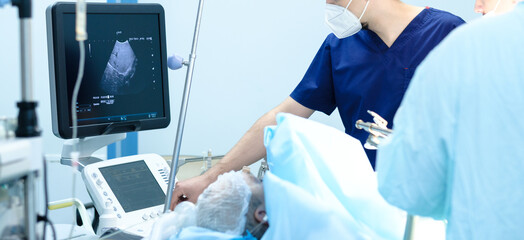 Ultrasound control of the patient's internal organs during surgery. Doctors look at an ultrasound monitor while operating on a person.