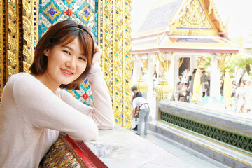 Fototapeta premium young asian woman tourist in Temple of Emerald Buddha (Wat Phra Kaew) in Bangkok, Thailand. Travel concept. Happy tourists. authentic people.