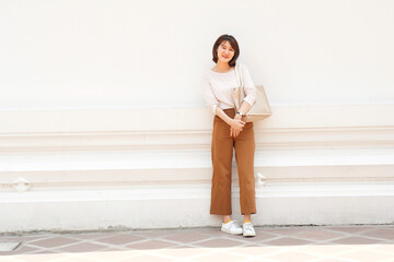 Asian woman in minimal dress pose front of white wall Temple in Bangkok, Thailand. Travel concept. Happy tourists. authentic people. Candid portraits.