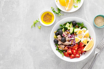 Tuna and fresh vegetable salad of tomato, cucumber, olives, onion, lettuce and boiled egg, top view