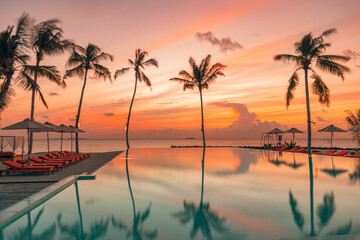 Fototapeta na wymiar Fantastic poolside, sunset sky, palm trees reflection. Luxury tropical beach landscape, infinity swimming pool, deck chairs and loungers under umbrellas amazing scenic. Vacation resort hotel landscape
