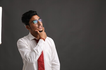 Young indian business man or employee thinking on dark background.