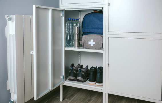 Emergency backpack and first aid kit kept in a closet at home - a white cabinet with a pair of shoes
