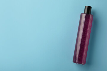 Bottle of pink cosmetic gel on light blue background, top view. Space for text