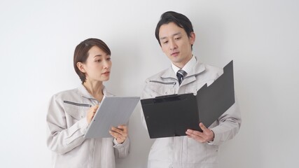 タブレット・ファイルを持ち話す作業着を着たビジネスマン