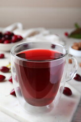 Glass cup of fresh dogwood tea on white marble board