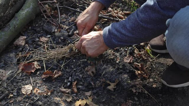 A man lights a fire with a flint