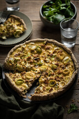 quiche aux poireaux et thon faite maison sur table avec salade et verre d'eau