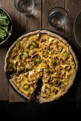 quiche aux poireaux et thon faite maison sur table avec salade et verre d'eau