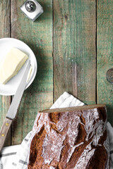 Fototapeta na wymiar Ein knuspriger Wecken Brot, Butter auf einem Teller und ein Salzstreuer auf einem rustikalen Holz Tisch. Draufsicht.