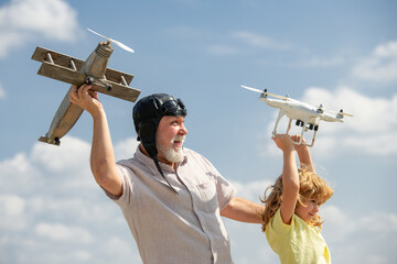Grandfather and grandson with plane and quadcopter drone over blue sky and clouds background. Elderly old relative with child.