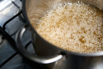 boiling caramel in a saucepan on a stove with many bubbles