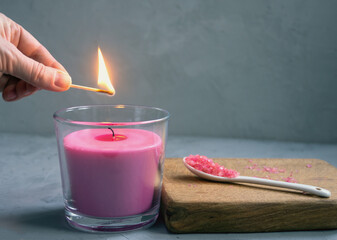 A woman lights a pink candle with a match