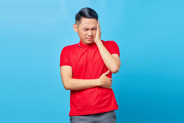 Portrait of handsome Asian young man in red shirt looking dizzy suffering from headache isolated on...
