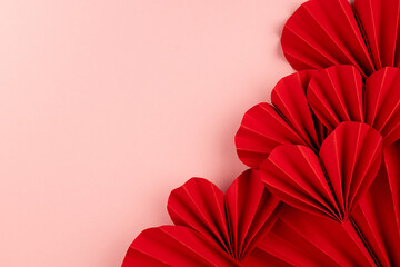 Passion love Valentine day background with red paper hearts of asian fans in modern fashion style on cute soft light pastel pink backdrop, closeup, sideways border, copy space, top view.