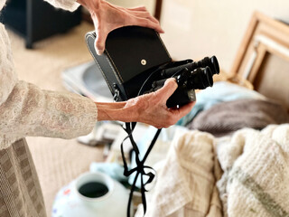 Obraz premium 片付け中に双眼鏡を出す高齢女性の手元