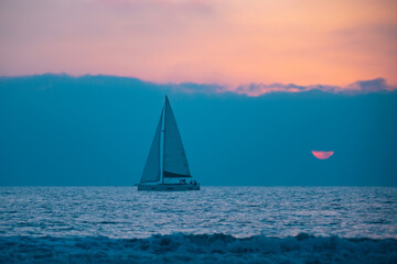 Fototapeta na wymiar Yacht sailing in the sunrise time. Sea landscape view with a beautiful sailboat. Yachting tourism sea voyage on the sail boat. Romantic trip on the sail vessel.