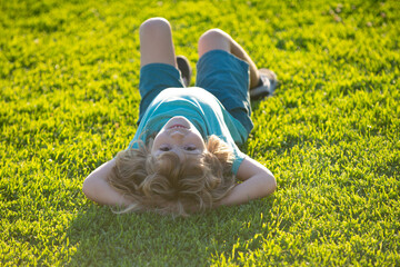Happy child laying upside down on green grass in summer Park. The concept of a healthy lifestyle....