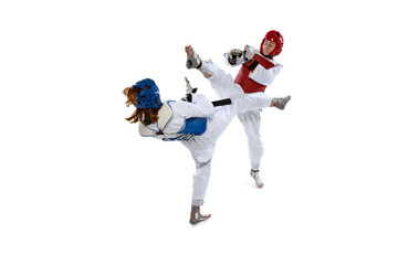 Fototapeta na wymiar Portrait of two young women, taekwondo athletes practicing, fighting isolated over white background. Concept of sport, skills