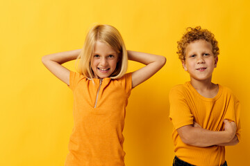 cheerful children in yellow t-shirts standing side by side childhood emotions yellow background