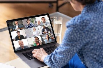 Aged business woman using laptop for having virtual team meeting on video call with different people, work from home office or coworking, online meeting, briefing, brainstorming