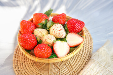 Fresh red and white strawberries in a wooden basket on wooden background, Red Strawberry and Pine berry or Hula strawberry in Bamboo basket.